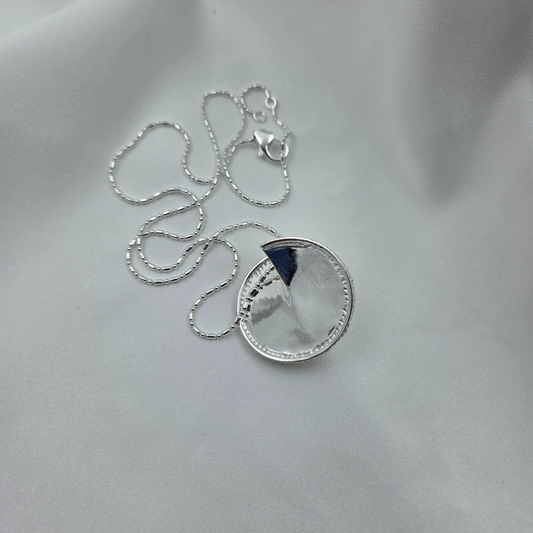 Silver necklace with a round pendant on a light gray background