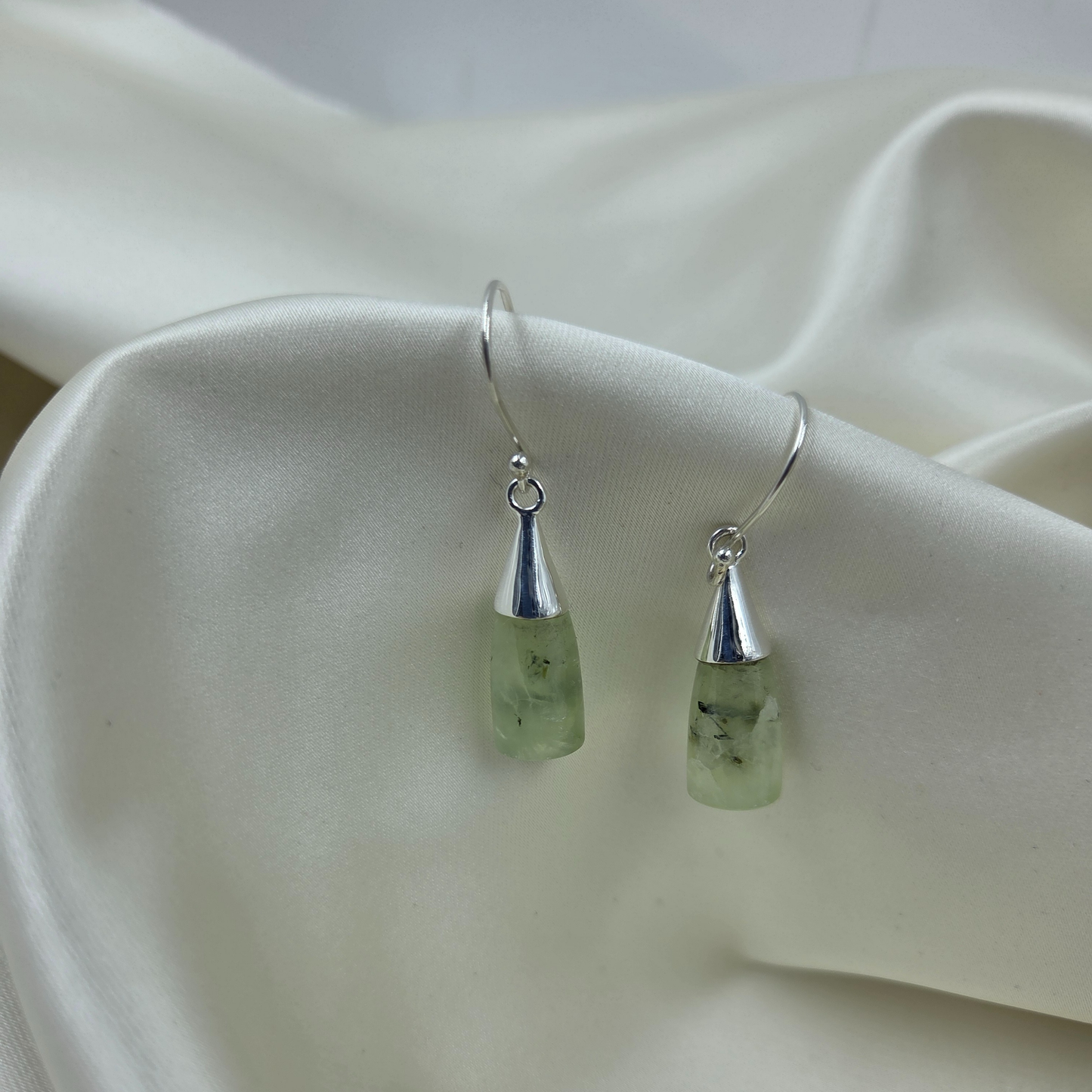 Pair of Prehnite silver earrings on a white fabric background