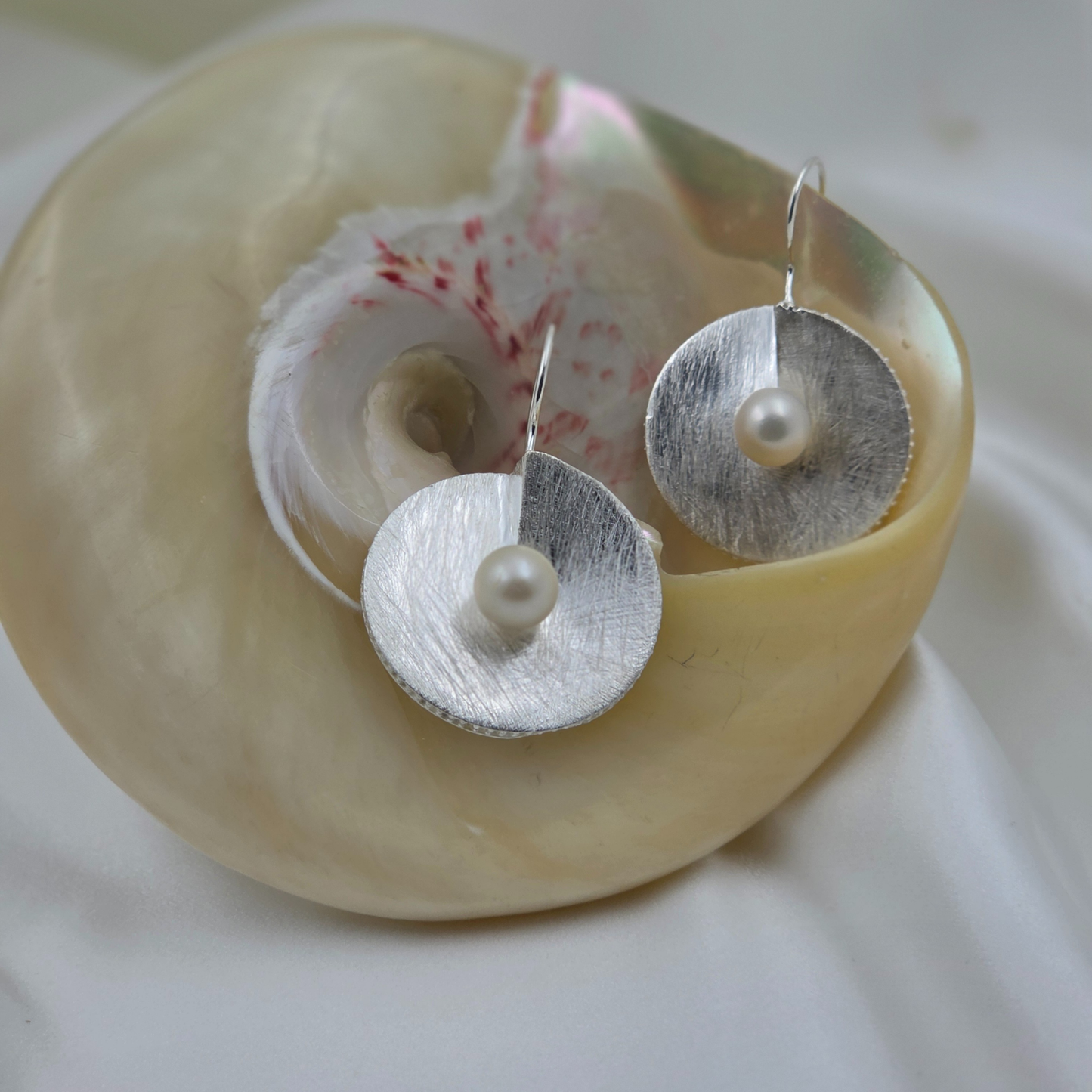 silver earring with a pearl at the centre on a shell