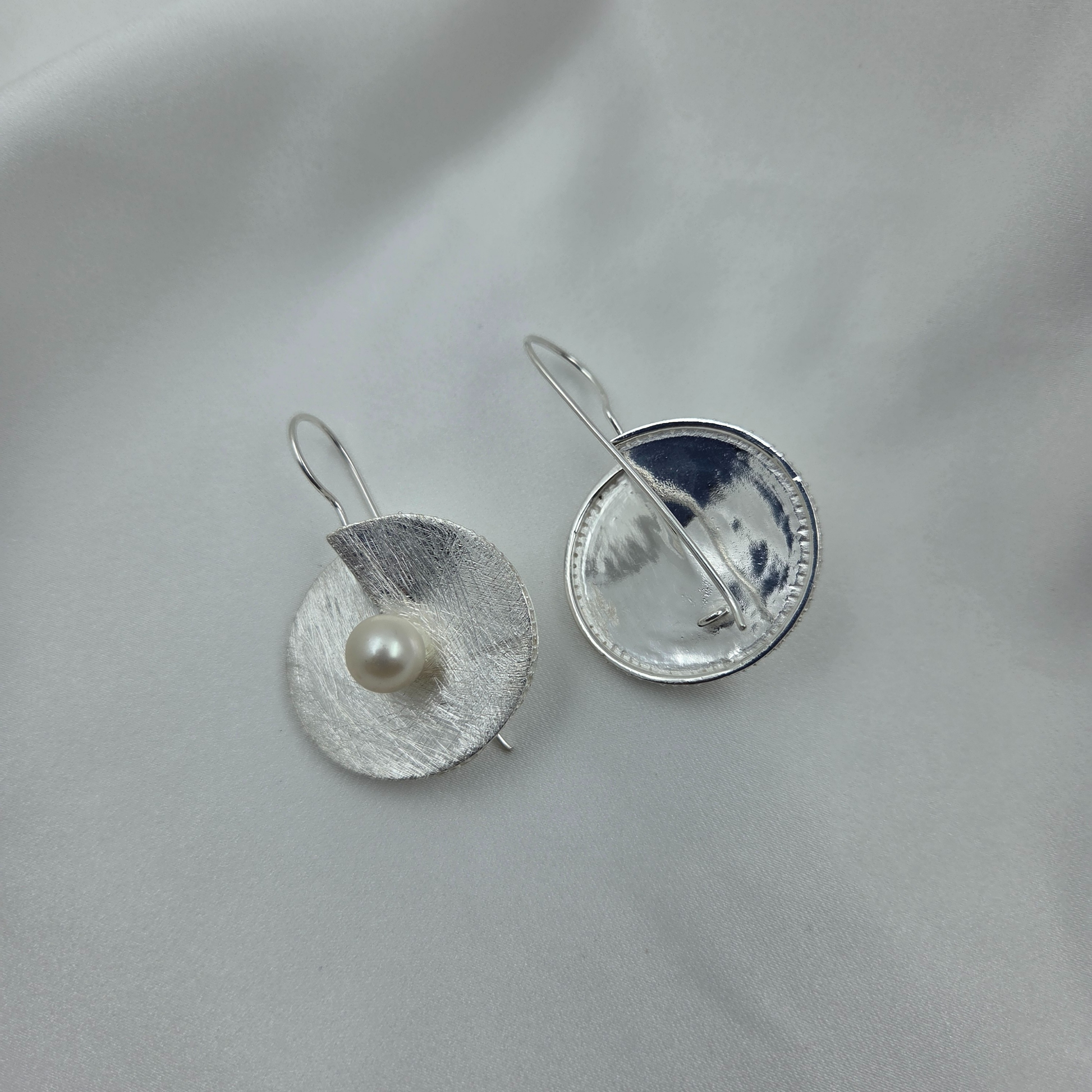 Silver  Earring - disc with a pearl at the centre on a light gray background