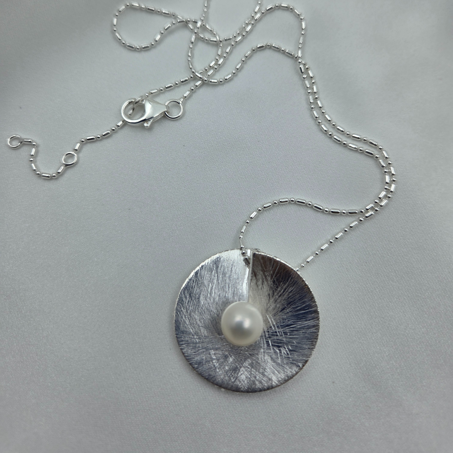 Silver disc with a pearl in the centre necklace  on a gray background