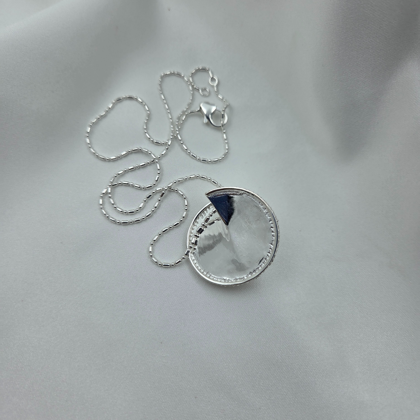 Silver necklace with a round pendant on a light gray background