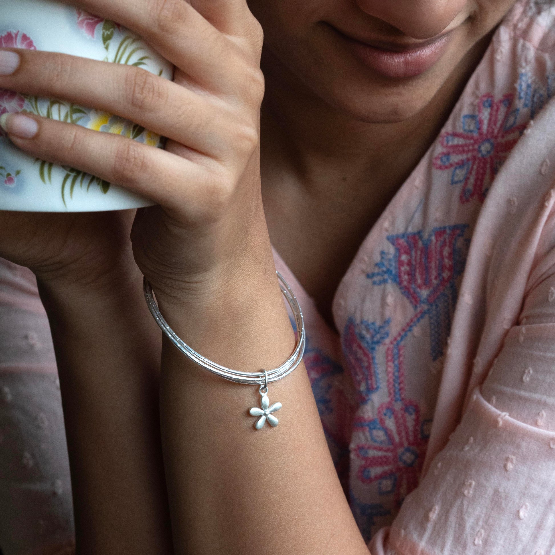 a polished silver cluster bangles bracelet with a small flower charm 