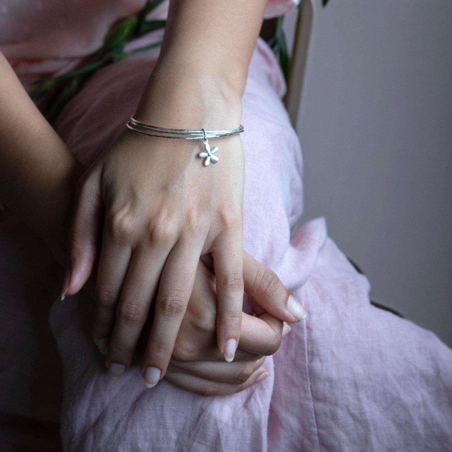 silver bangle bracelet with a small flower charm.