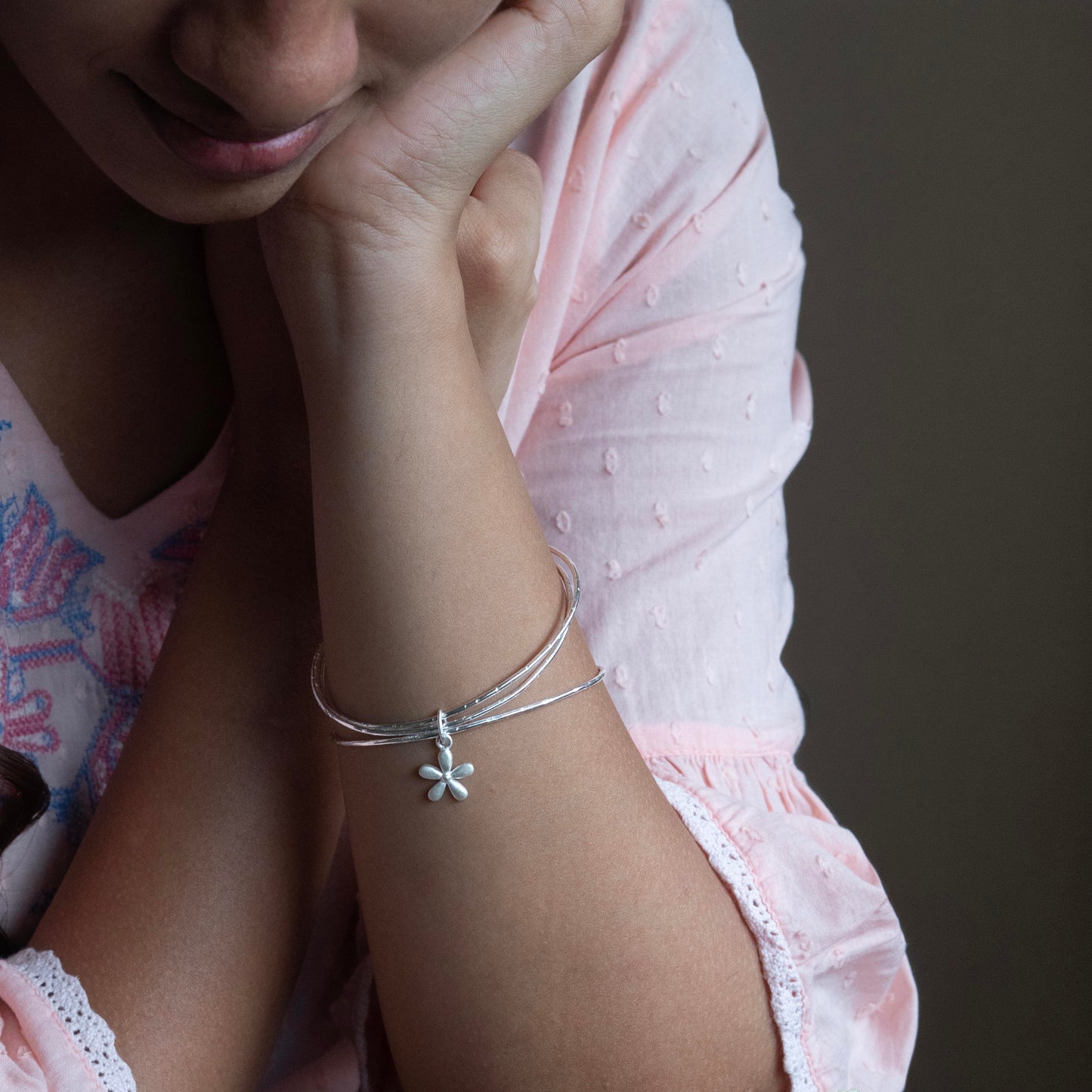 a delicate silver bracelet with a small flower charm