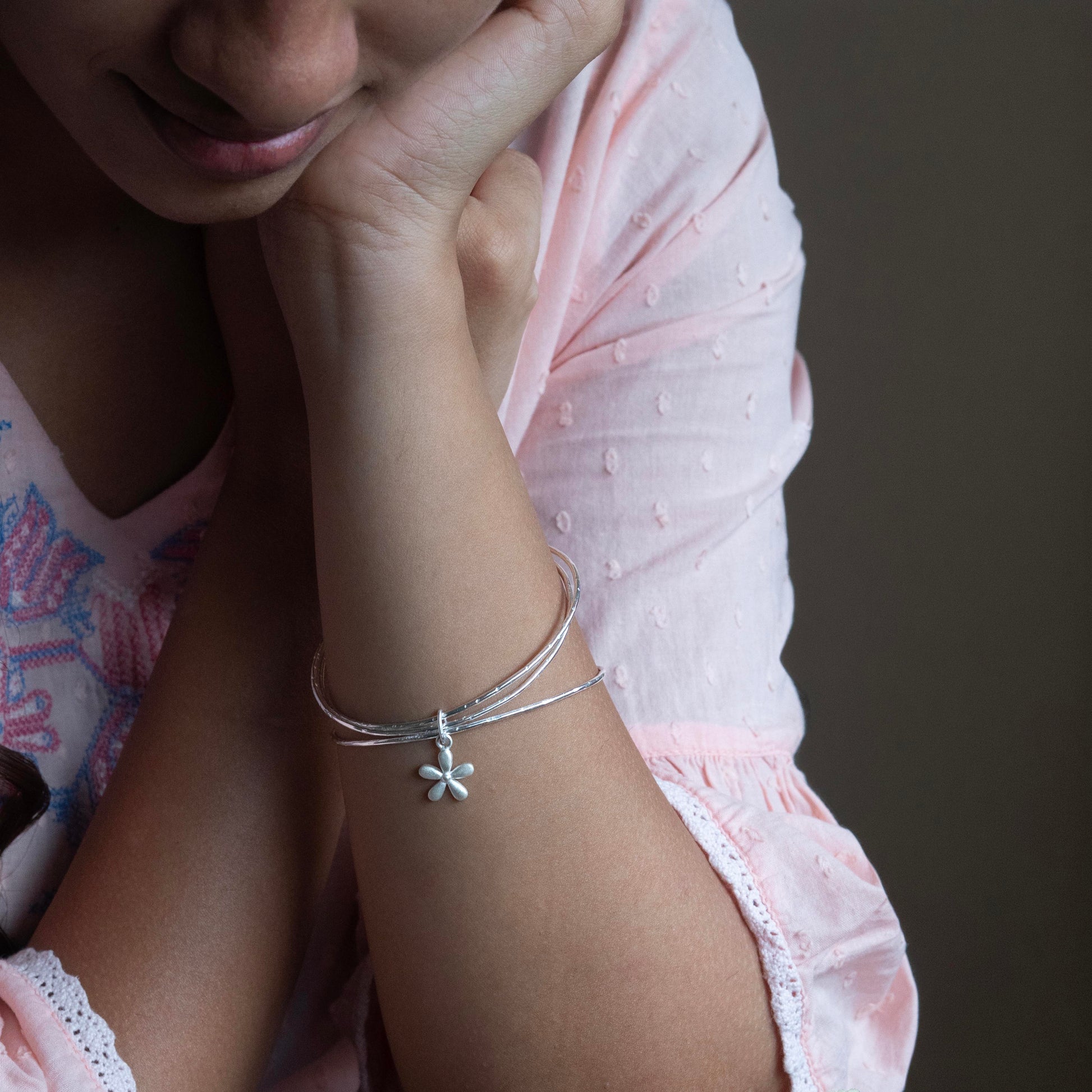 a delicate silver bracelet with a small flower charm