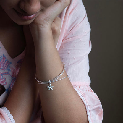 a delicate silver bracelet with a small flower charm