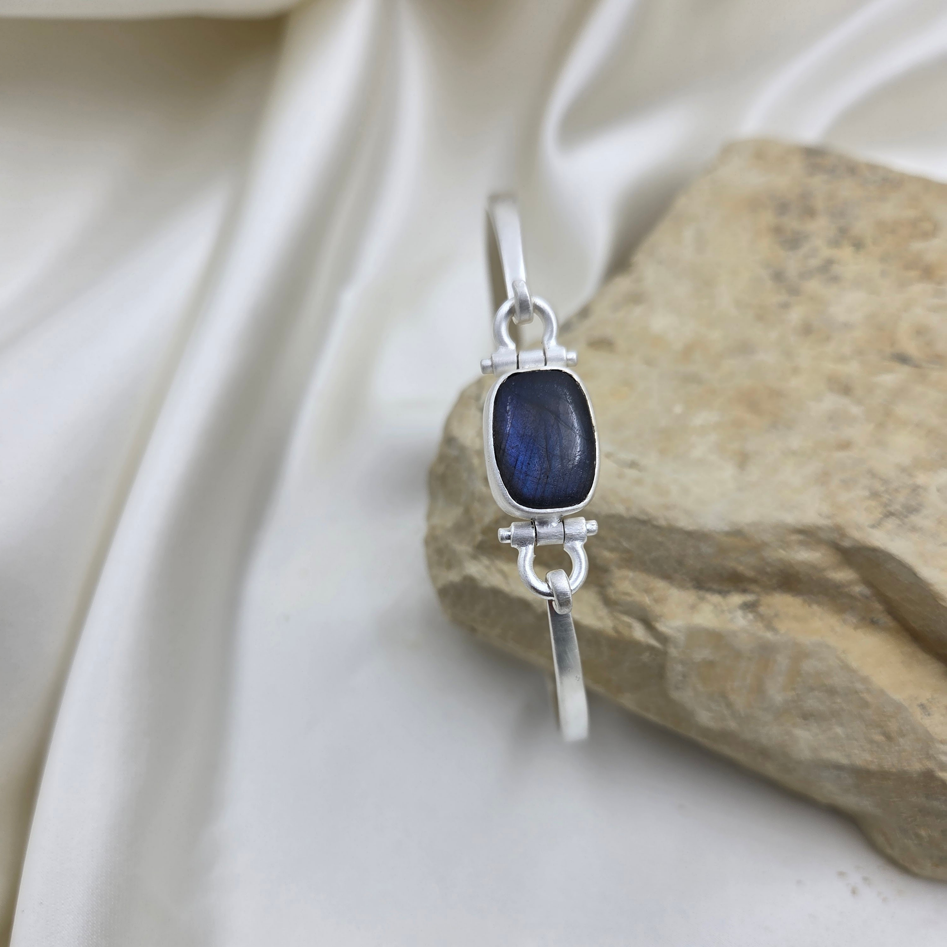 Silver bracelet with a blue stone on a beige fabric background