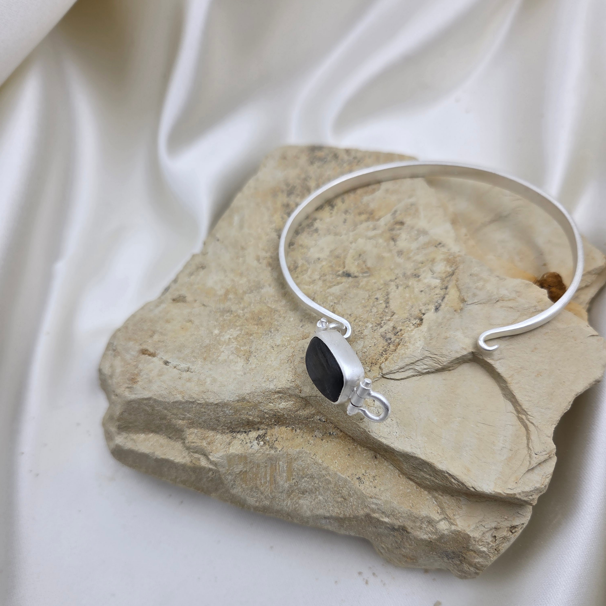 Silver bracelet with a black stone on a textured stone surface